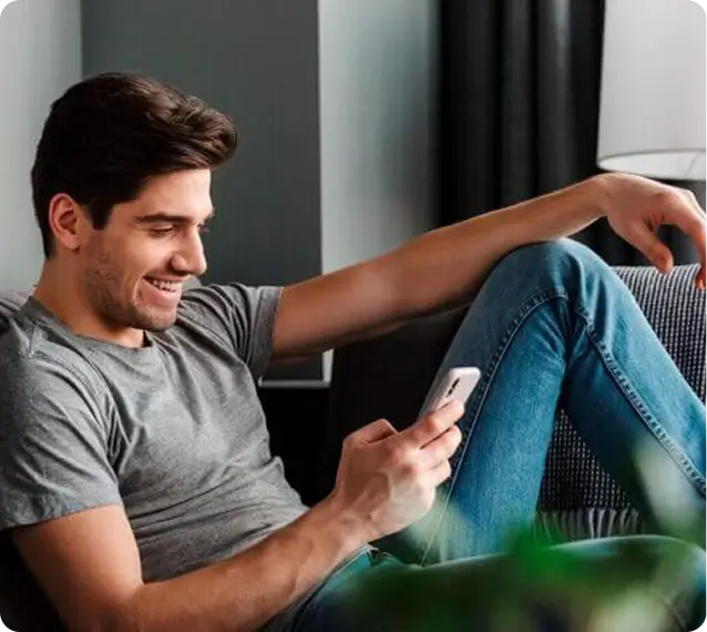 man in blue jeans looking at his phone and smiling