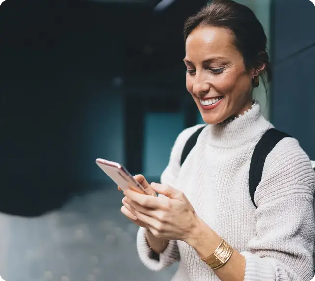 lady in sweater smiling at her phone