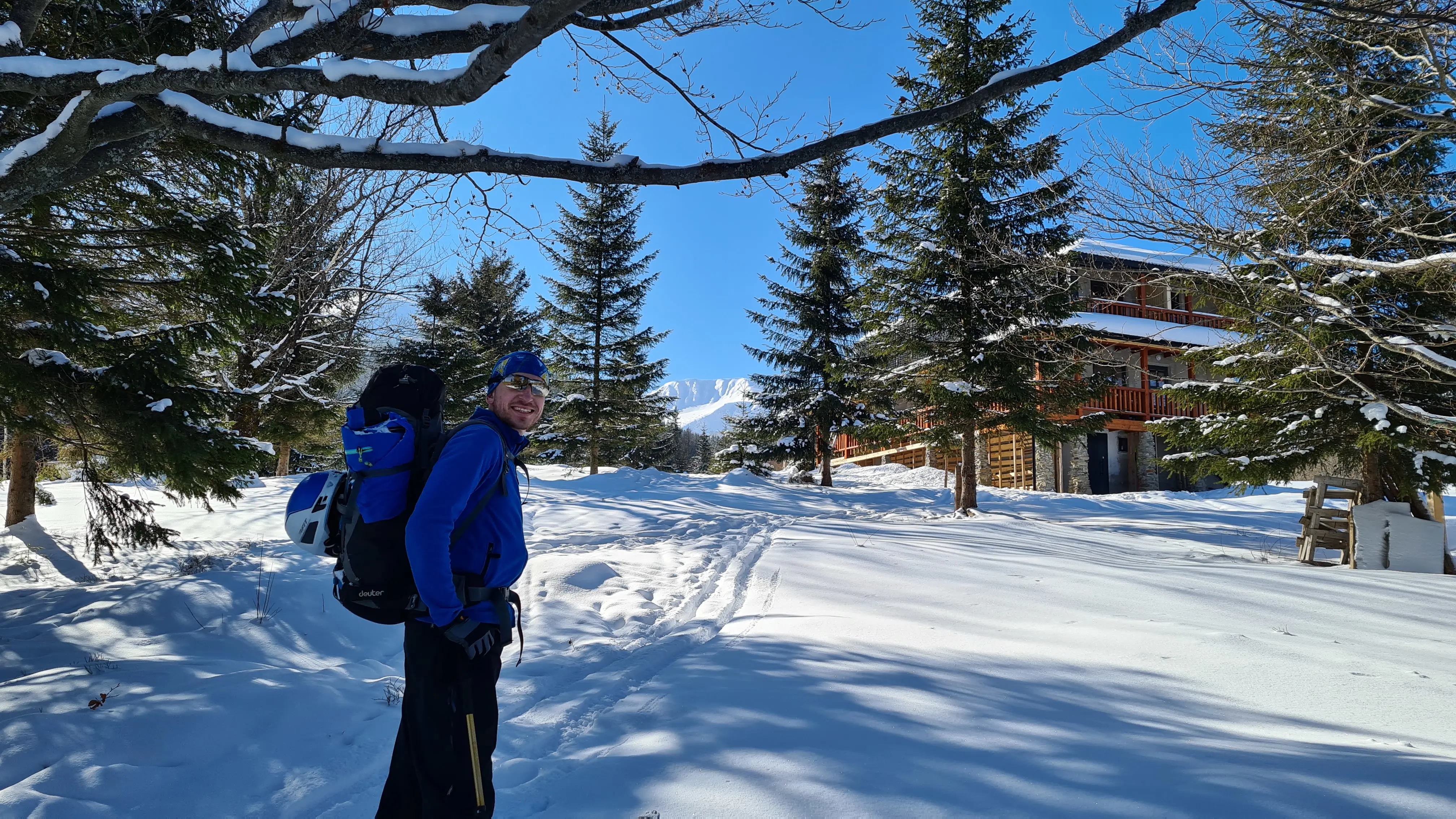 Роман Козачук у зимовому поході на фоні гір та котеджу.