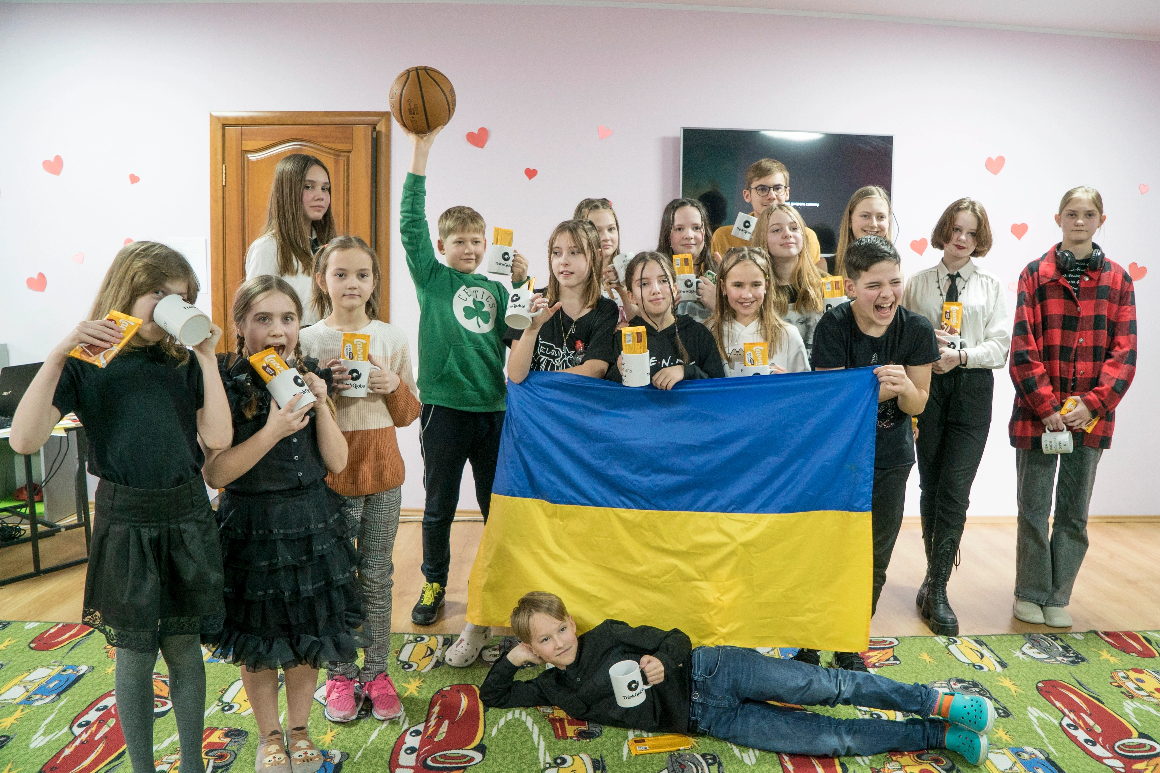  ThinkGlobal middle school students with the Ukrainian flag and corporate prizes at a school event.