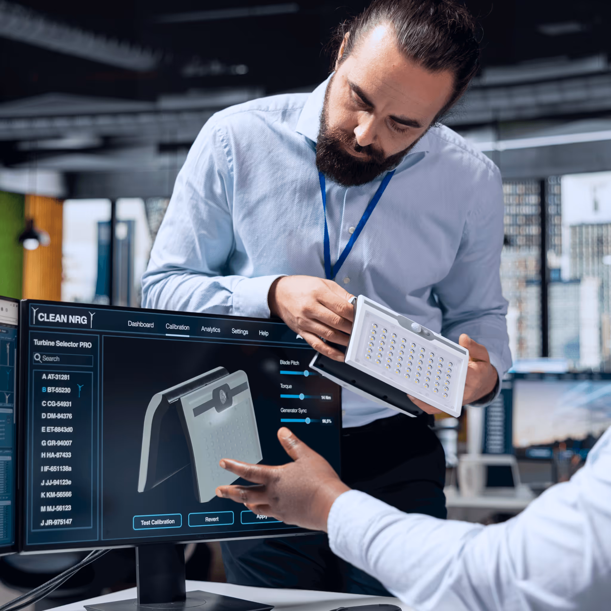 Technical discussion between colleagues about clean energy technology, with a focus on a device and turbine selector software in a well-lit office.