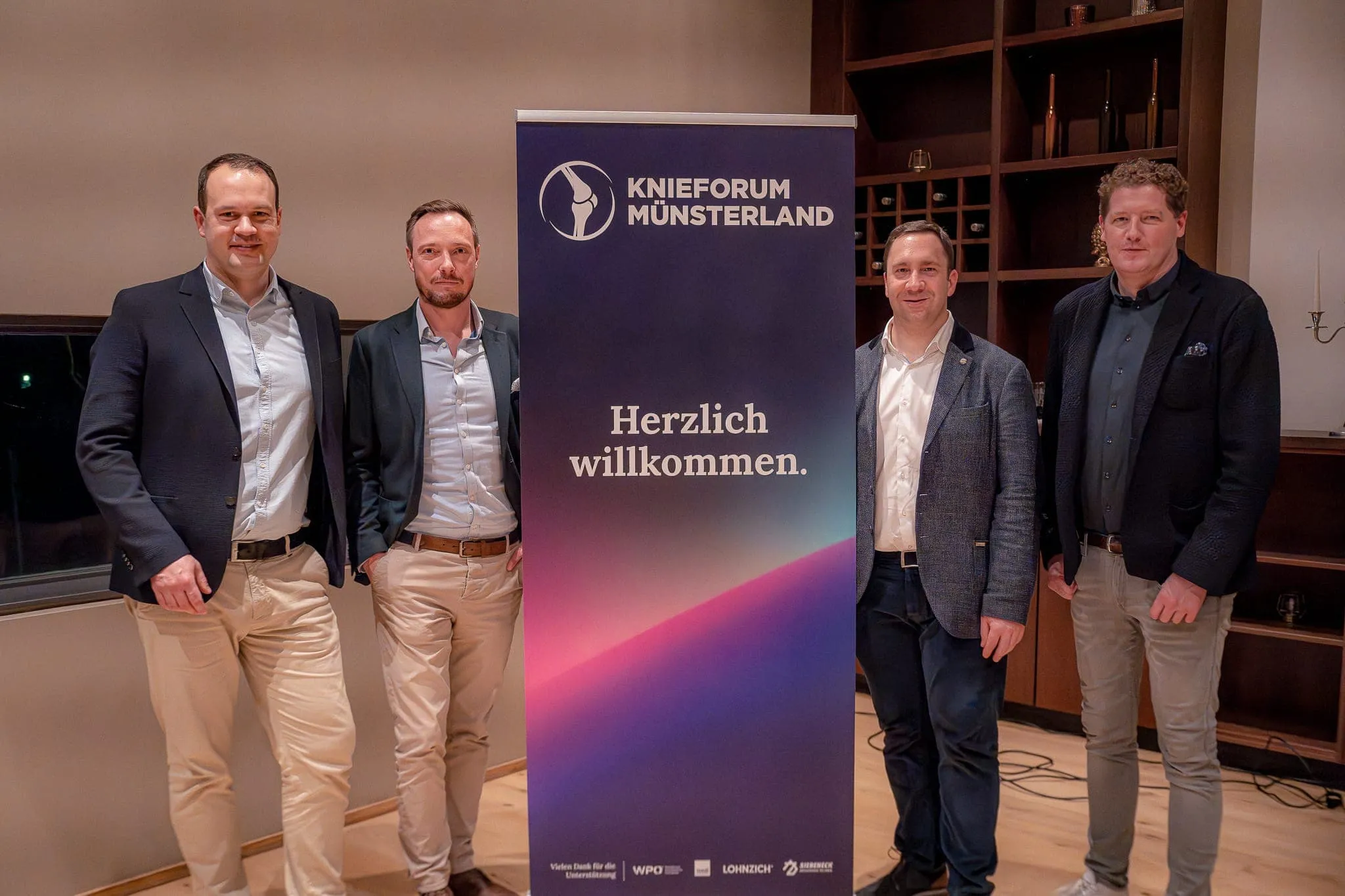 Gruppenfoto vor dem Willkommensbanner des Knieforum Münsterland 2023