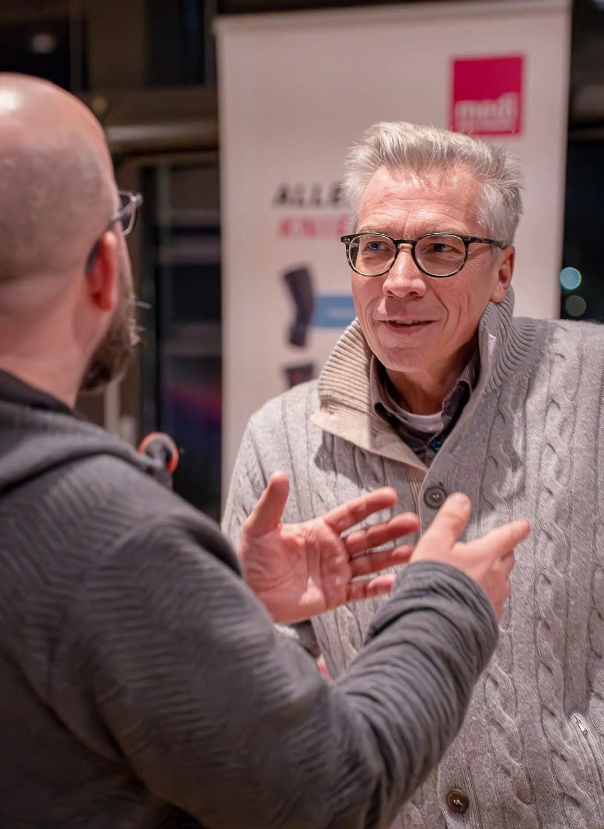 Teilnehmer im Gespräch vor einem Infostand beim Knieforum Münsterland