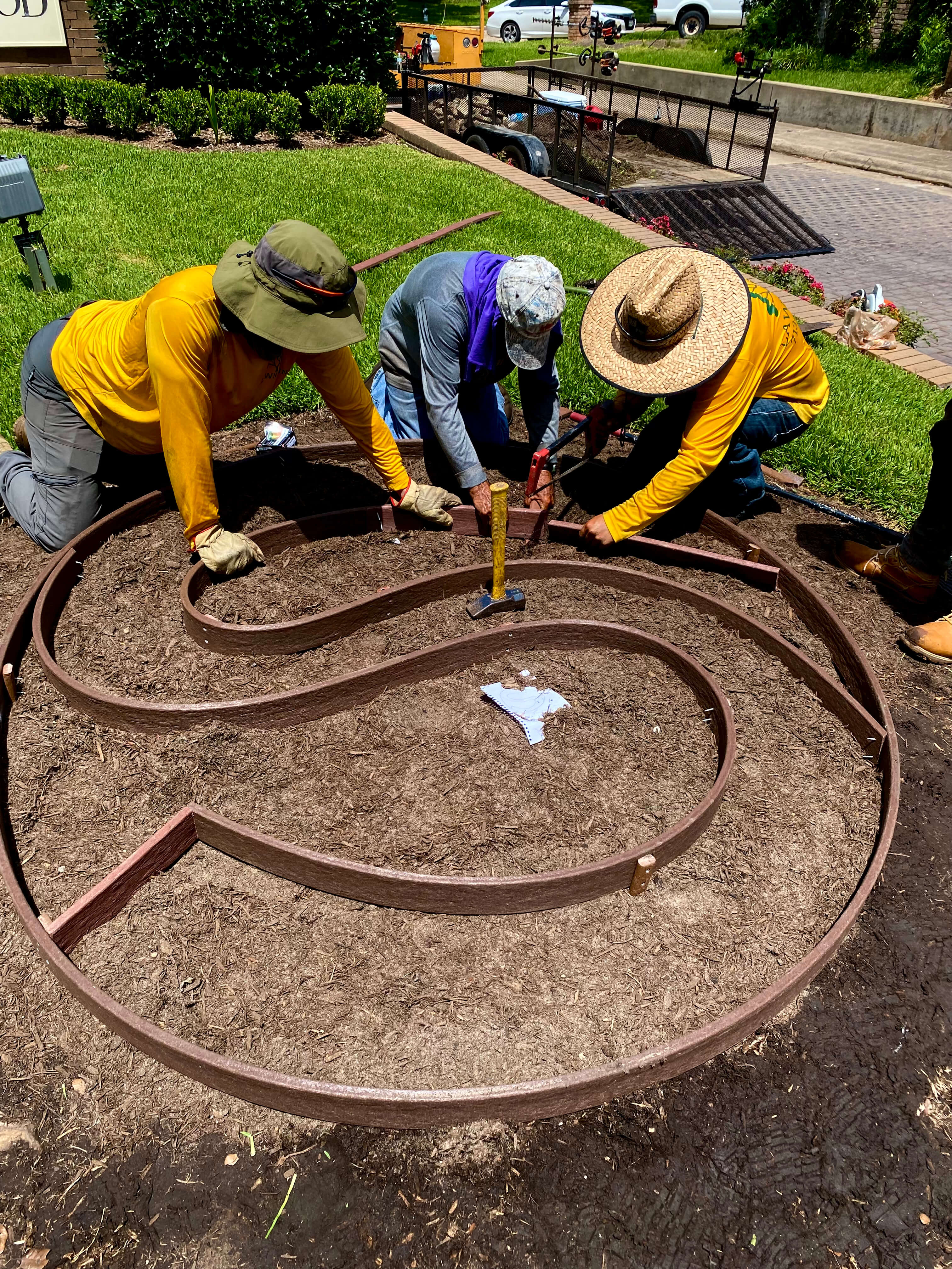 Lawn John crew installing a custom annual color bed emblem for a commercial property entrance.