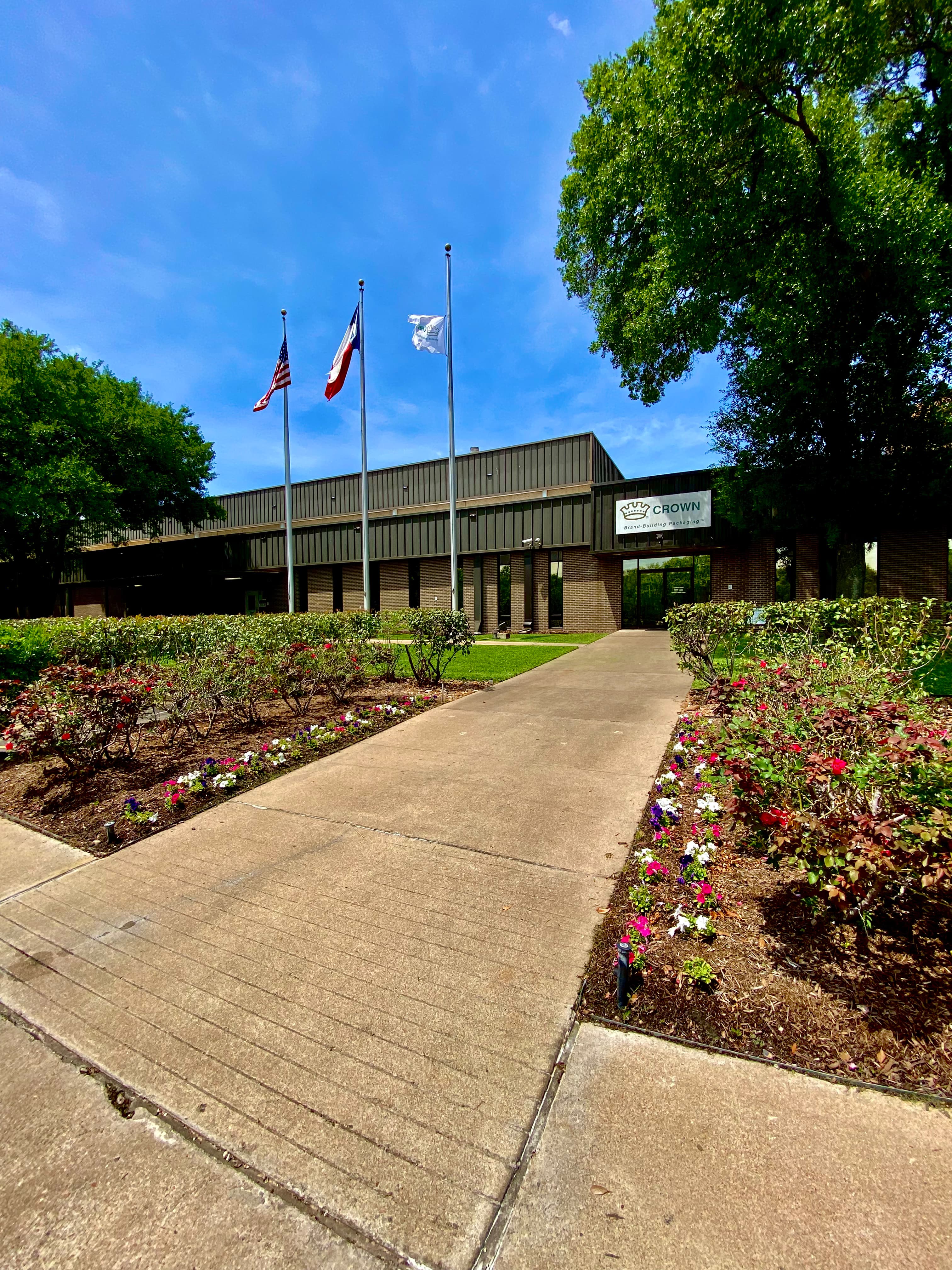 Commercial building landscape maintenance with clean lawn, trimmed shrubs, and seasonal color beds