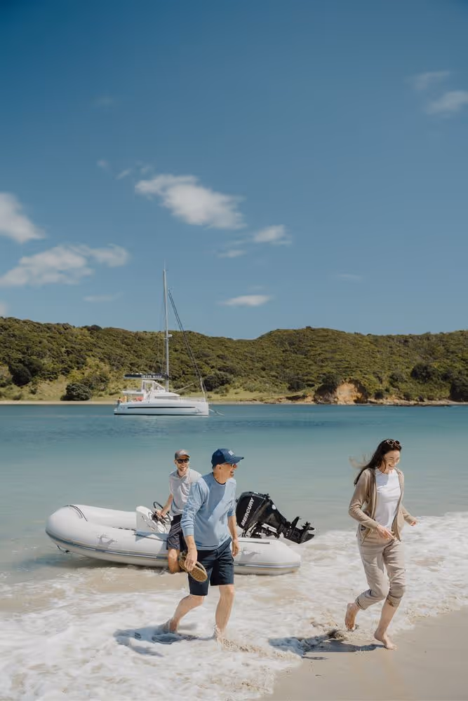 Couple step ashore from tender with yacht in the background