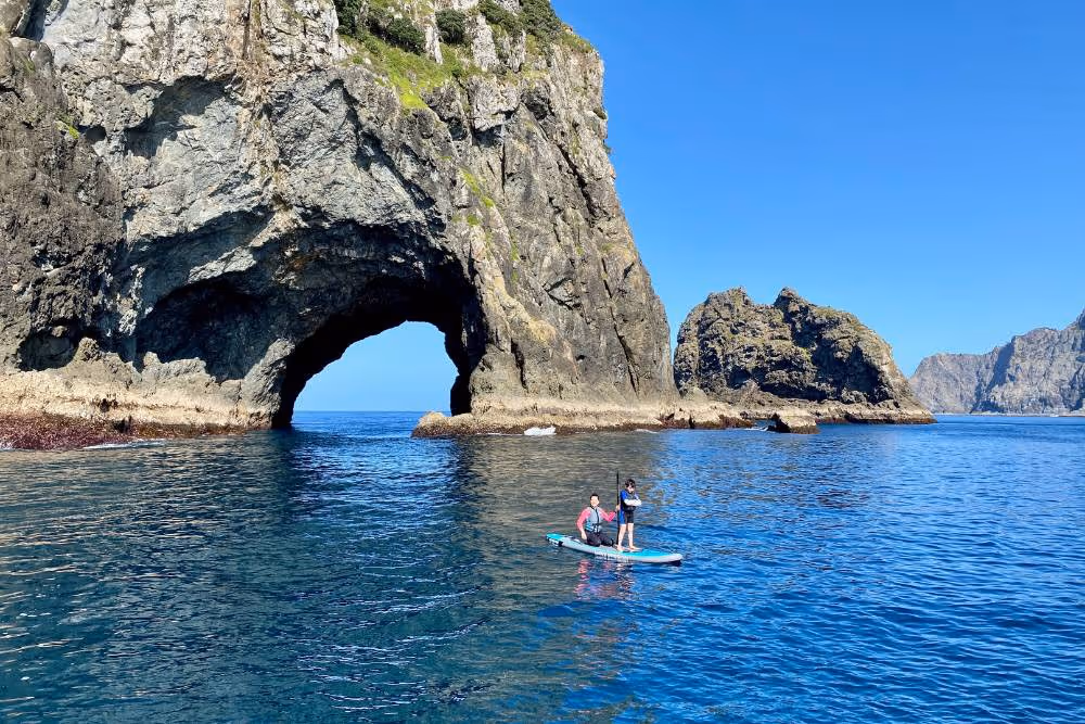 Guests paddleboard through the Hole in the Rock