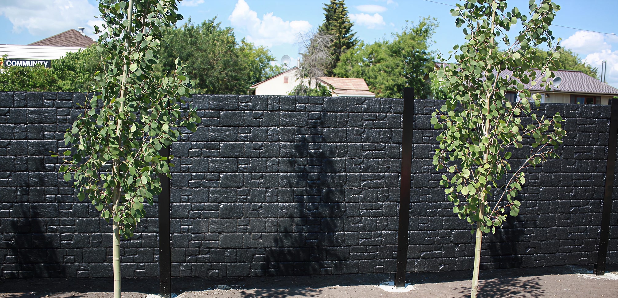 Black EcoFlex sound barrier walls with small trees in front