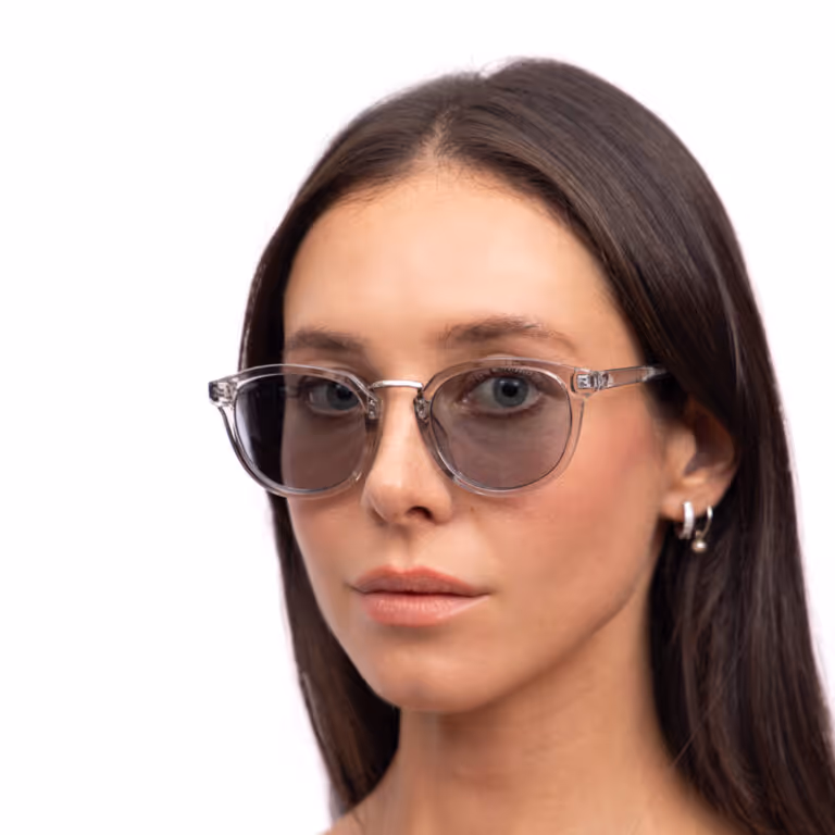 Woman with long dark hair wearing transparent framed sunglasses and silver hoop earrings with a pearl.