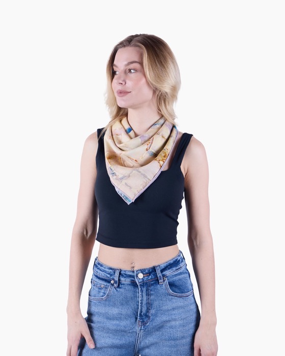 Young woman wearing a black sleeveless crop top and blue jeans with a beige patterned scarf tied around her neck.