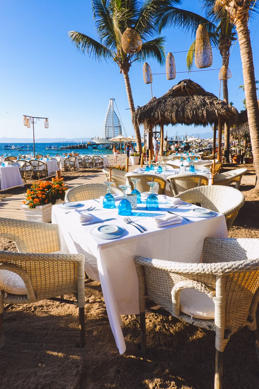 Tables set for breakfast on the sand at El Dorado, with the Los Muertos pier beyond