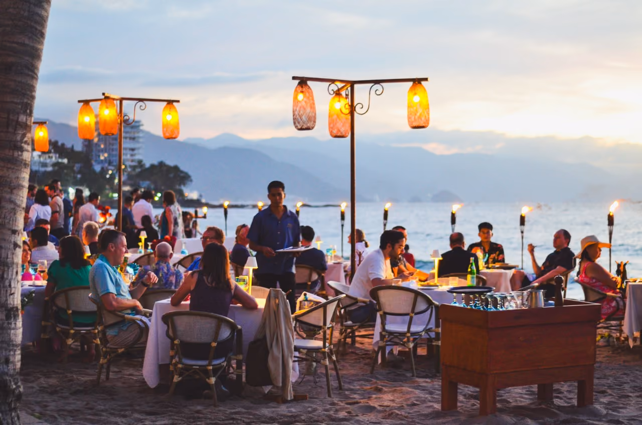 Evening dinner service on the sand at El Dorado, lanterns lit along the beach