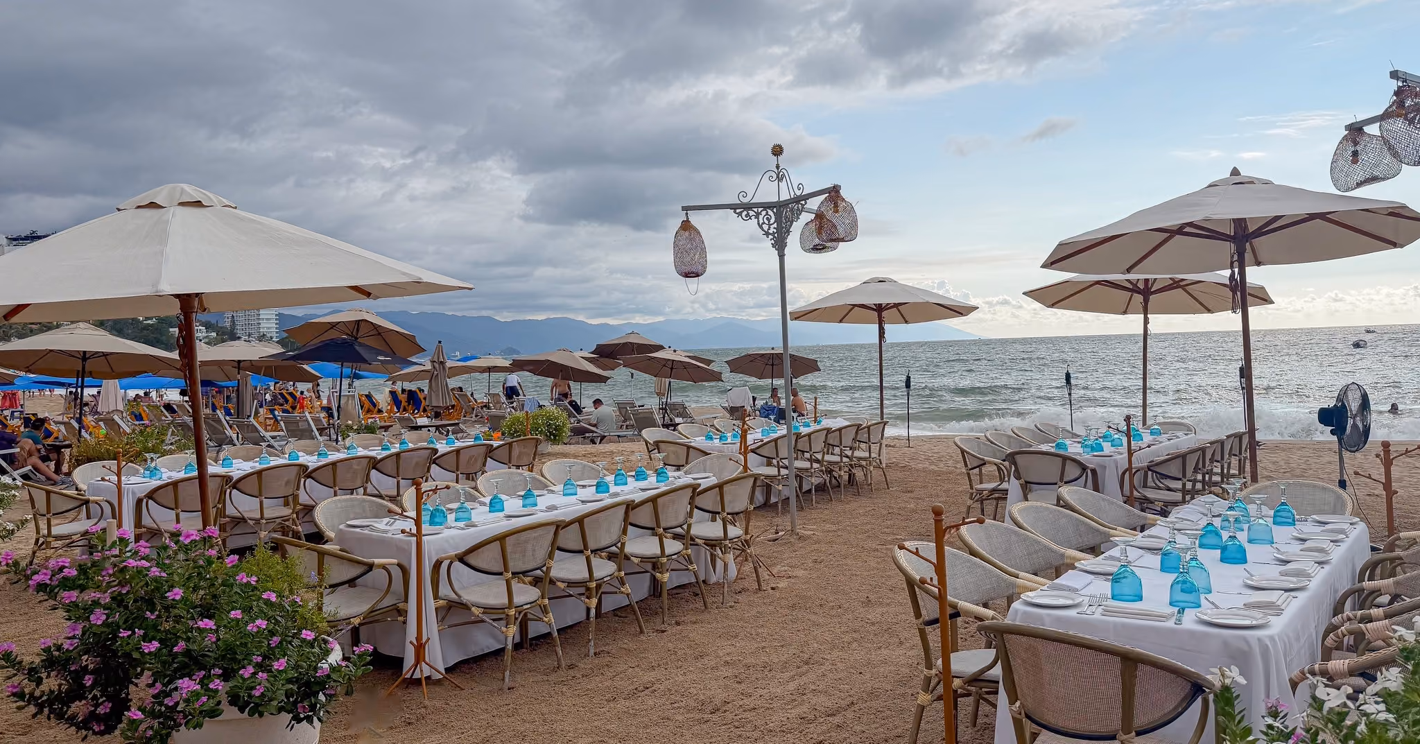 Long tables set on the sand for an event at El Dorado, facing the ocean