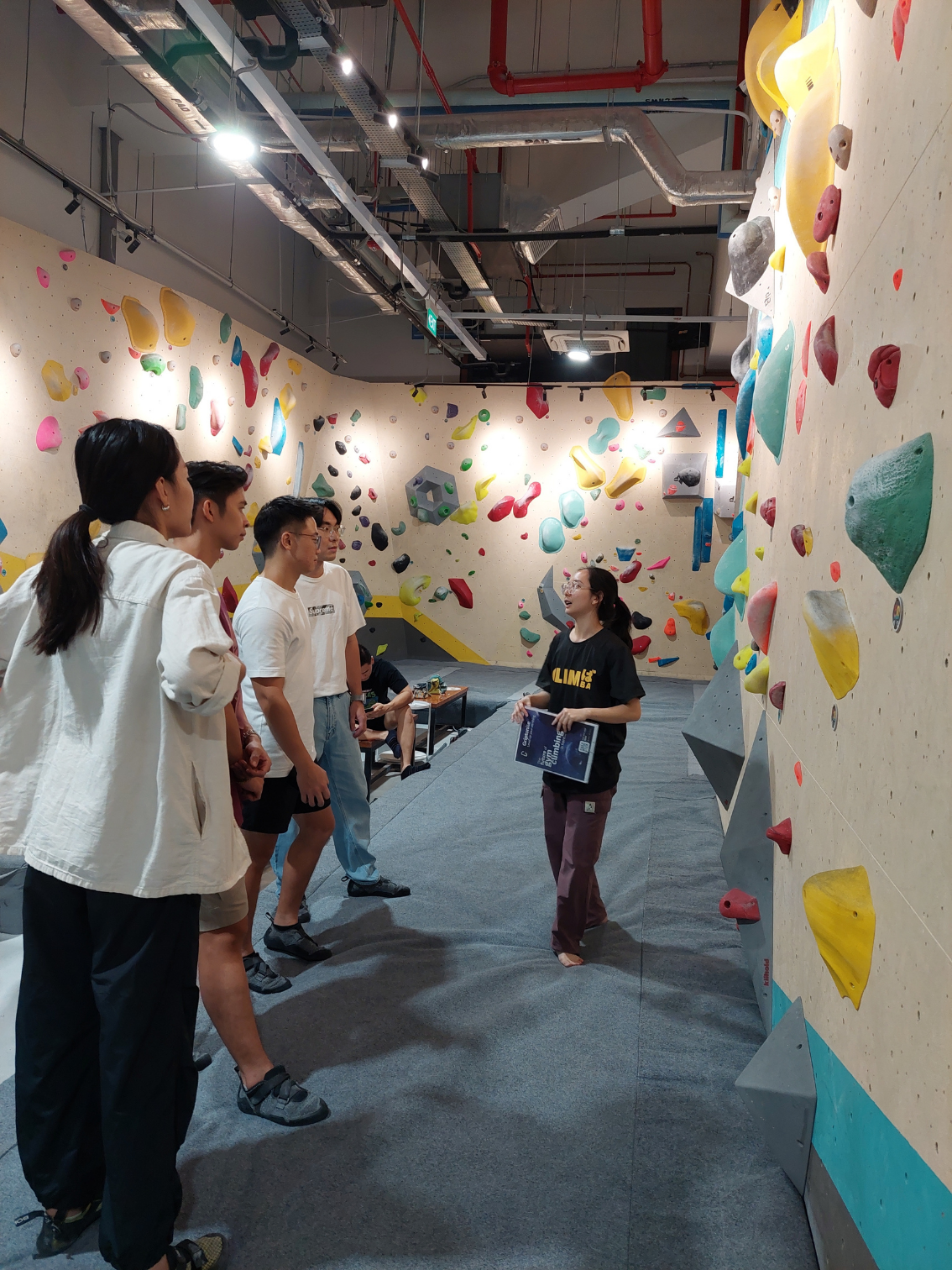 Climba coach demonstrating proper hand position to a beginner climber