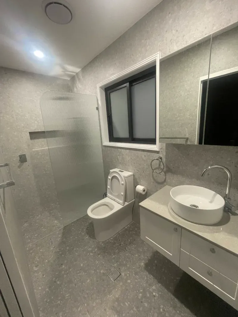 Granny flat bathroom with terrazzo tiles, fluted glass shower screen and wall-hung vanity