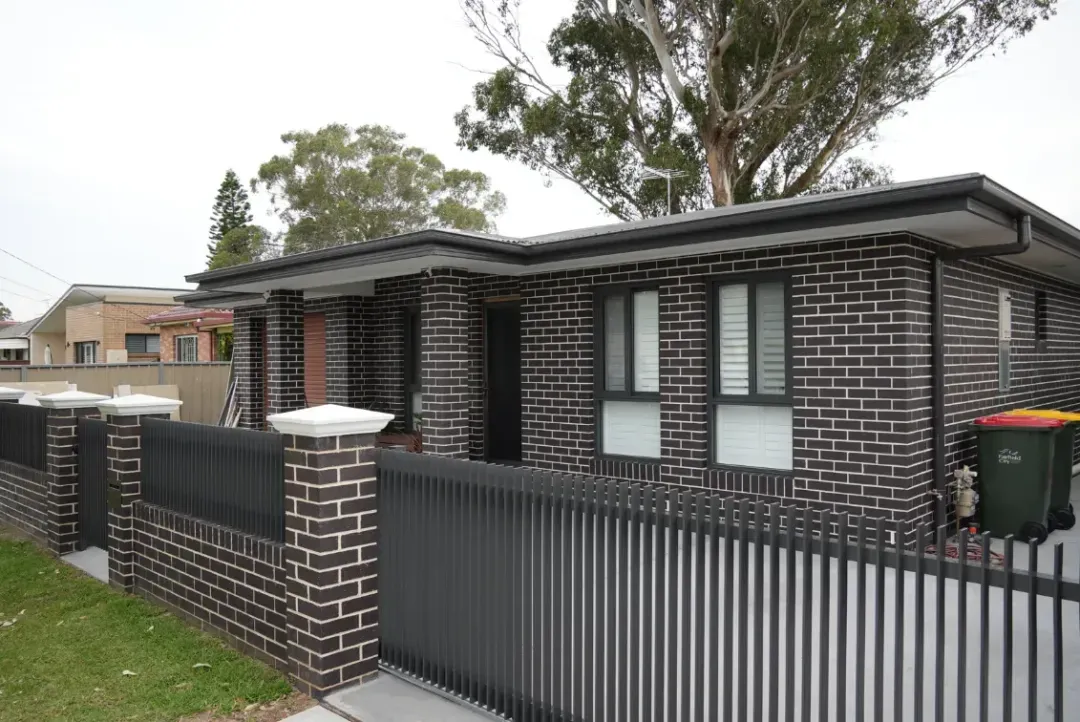Dark brick granny flat with a black fence, built by Kobo Projects in Fairfield