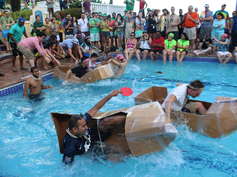 Teams racing cardboard boats in a pool during a FullTilt Boat Build event