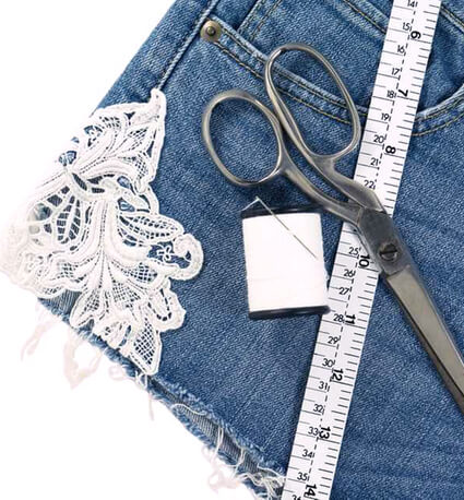 Abgeschnittene Jeanshose die mit upcycling zu aufgewertet wird, durch Spitzeneinlagen und andere Stoffapplikationen