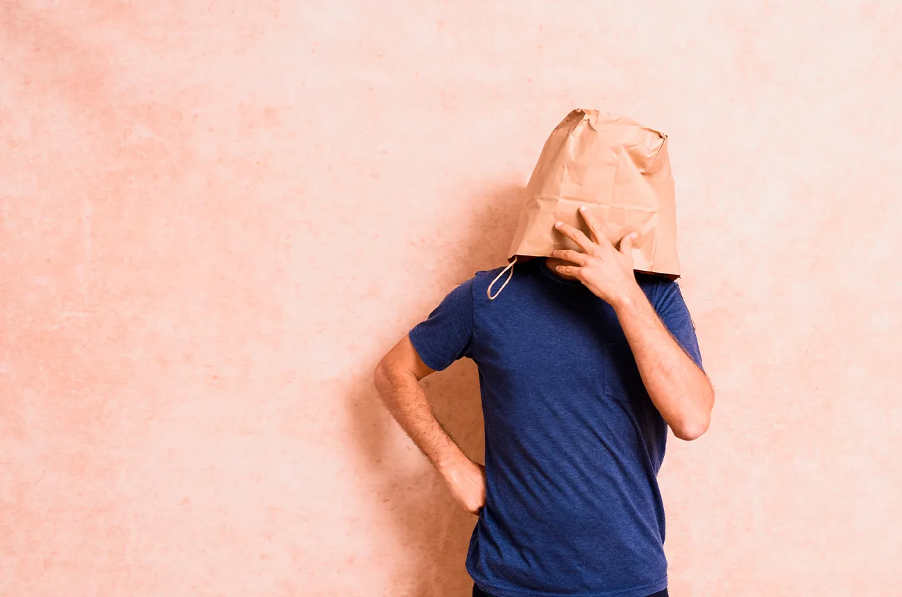 homme timide se cache derriere un sac par peur ou honte