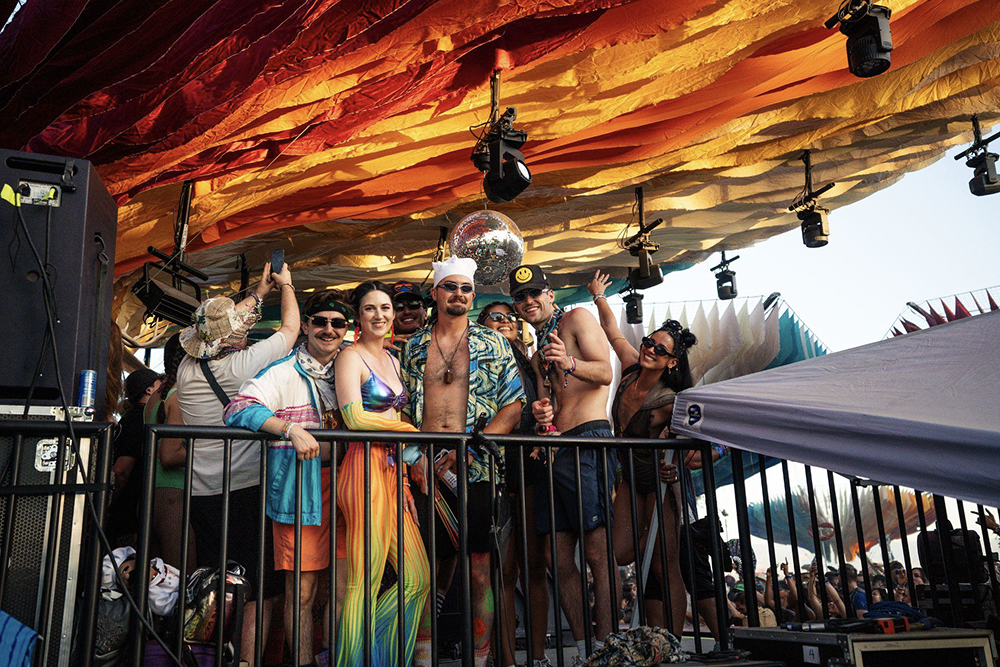 Festival production team gathered on stage under a colorful canopy, representing the human side of event operations supported by Billfold’s backend tools