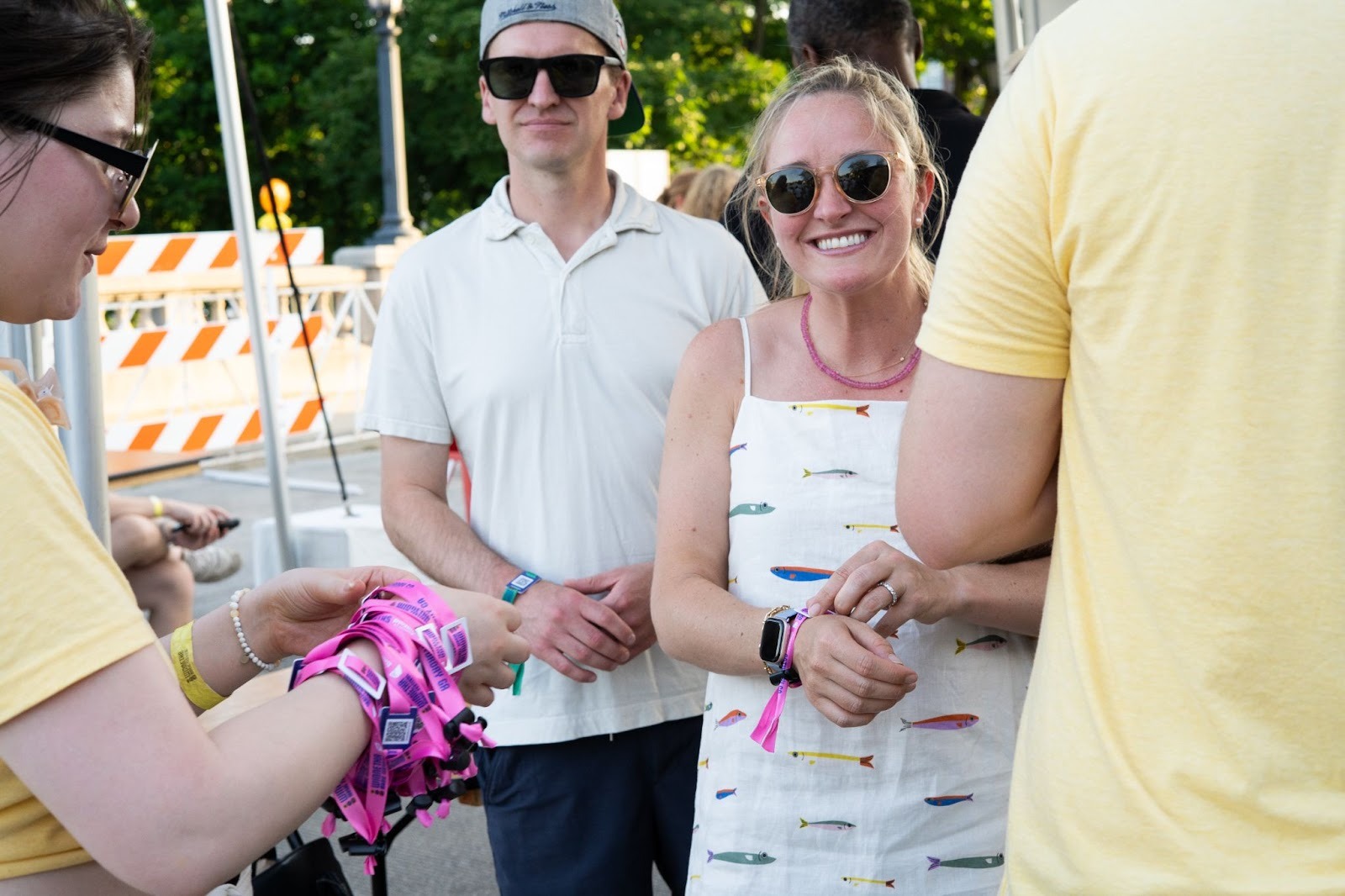 Festival attendee tapping RFID wristband on payment terminal at food booth with vendor smiling and tacos in background