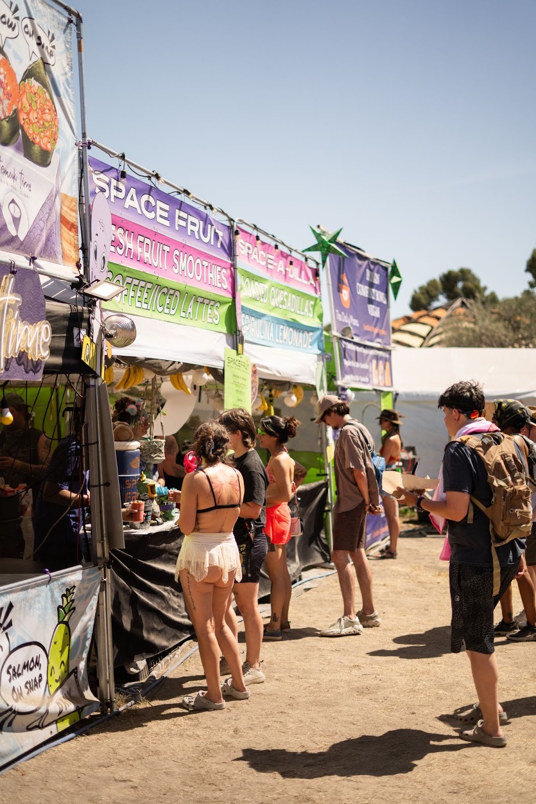 Festival attendees using RFID wristband payments at outdoor food vendor booth during music event