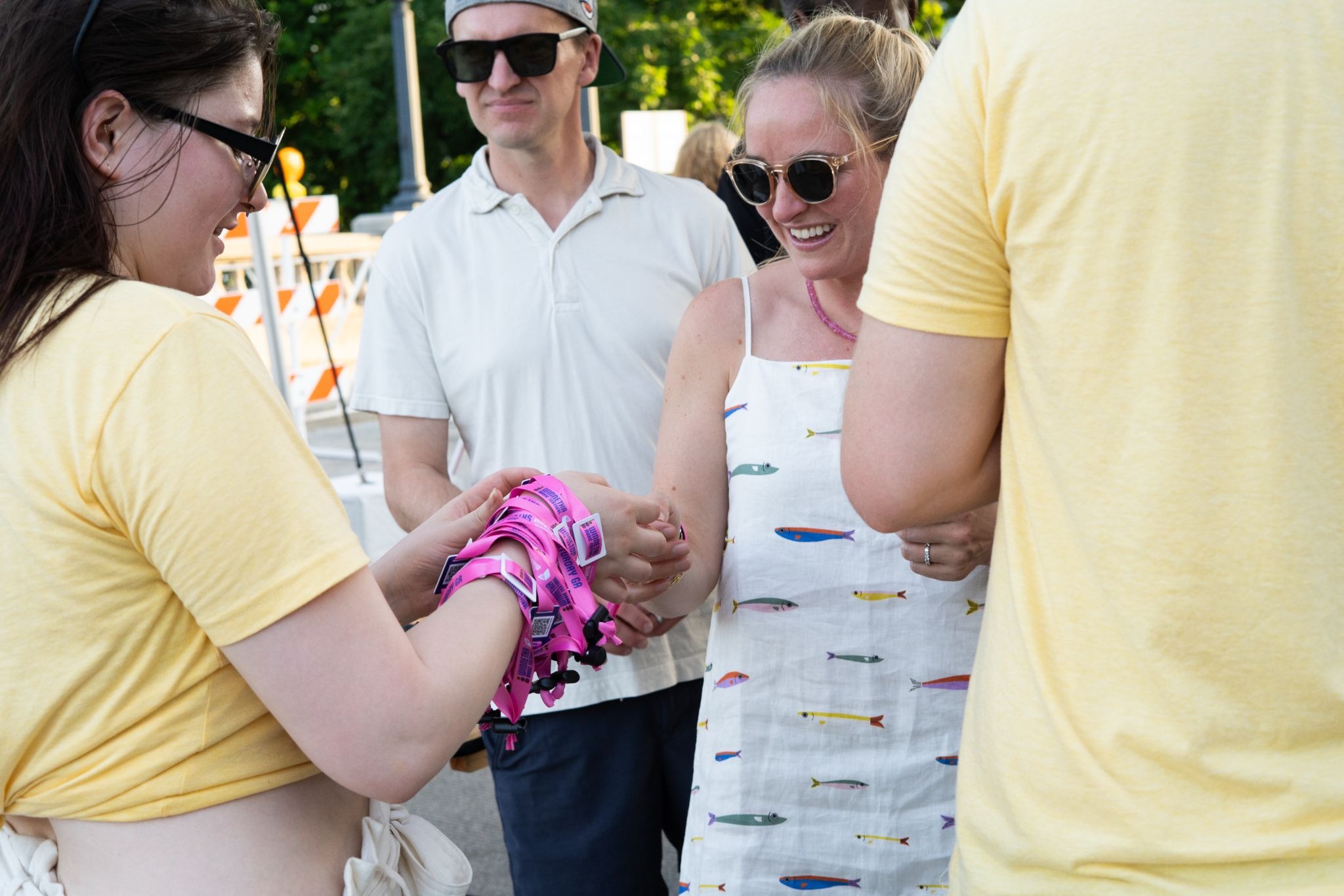 Event staff distributing pink RFID payment wristbands to attendees at outdoor festival entry checkpoint