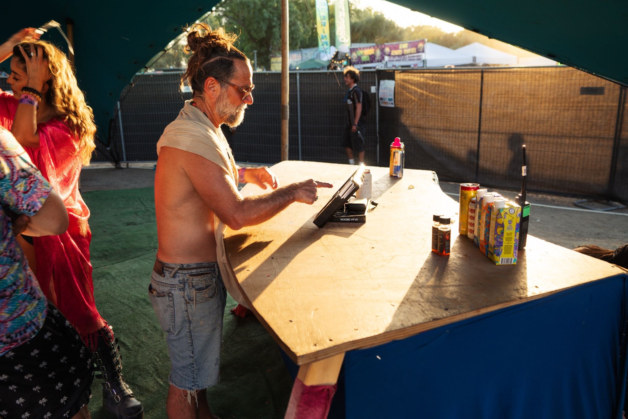 Festival vendor processing transaction on tablet payment terminal at outdoor booth during golden hour