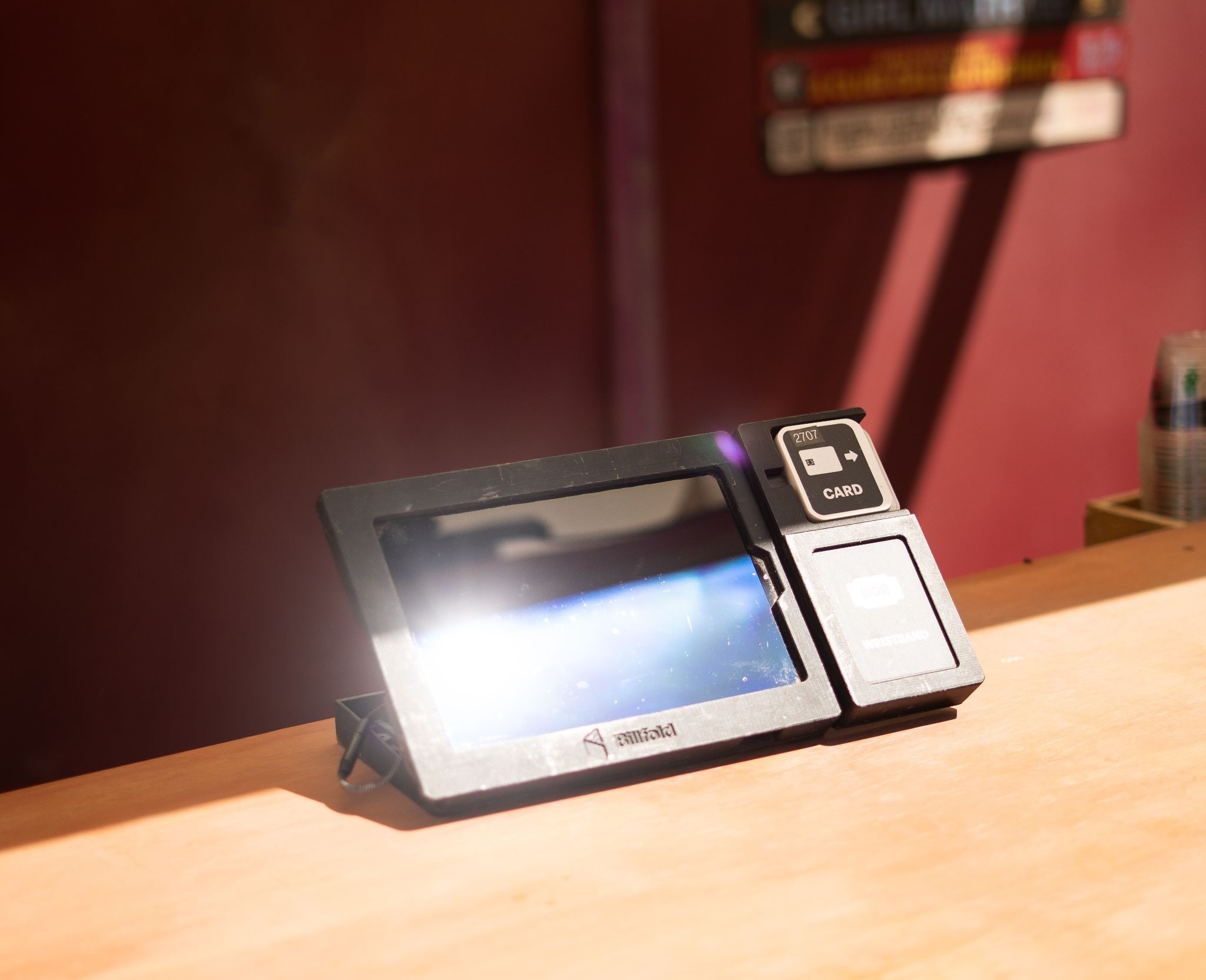Cashless POS payment tablet on a wooden counter at a concert venue concession stand under bright sunlight