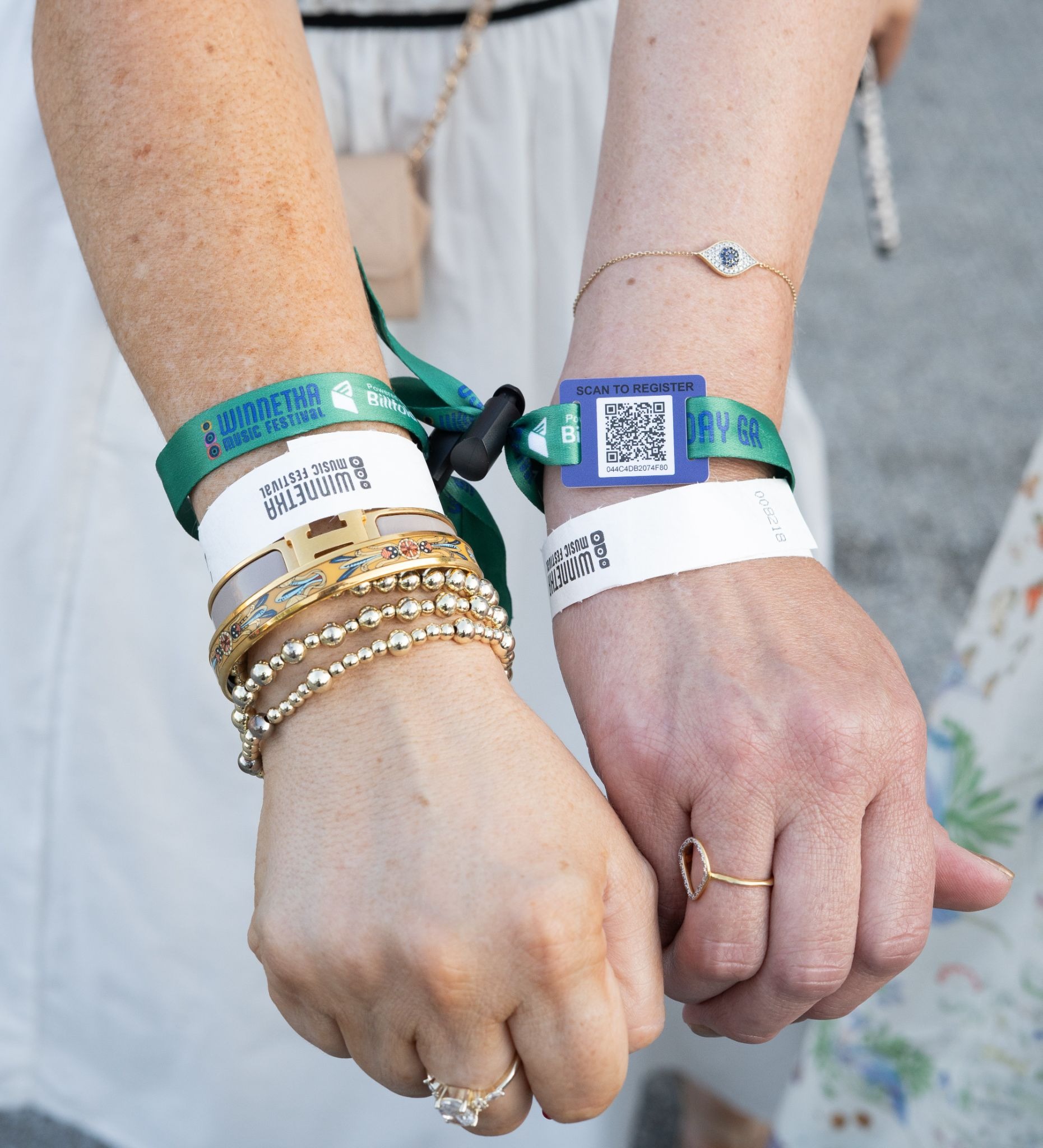 Close-up of two arms wearing multiple event wristbands at an outdoor music festival