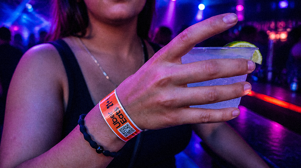 Guest holding a drink while wearing an event wristband in a nightclub