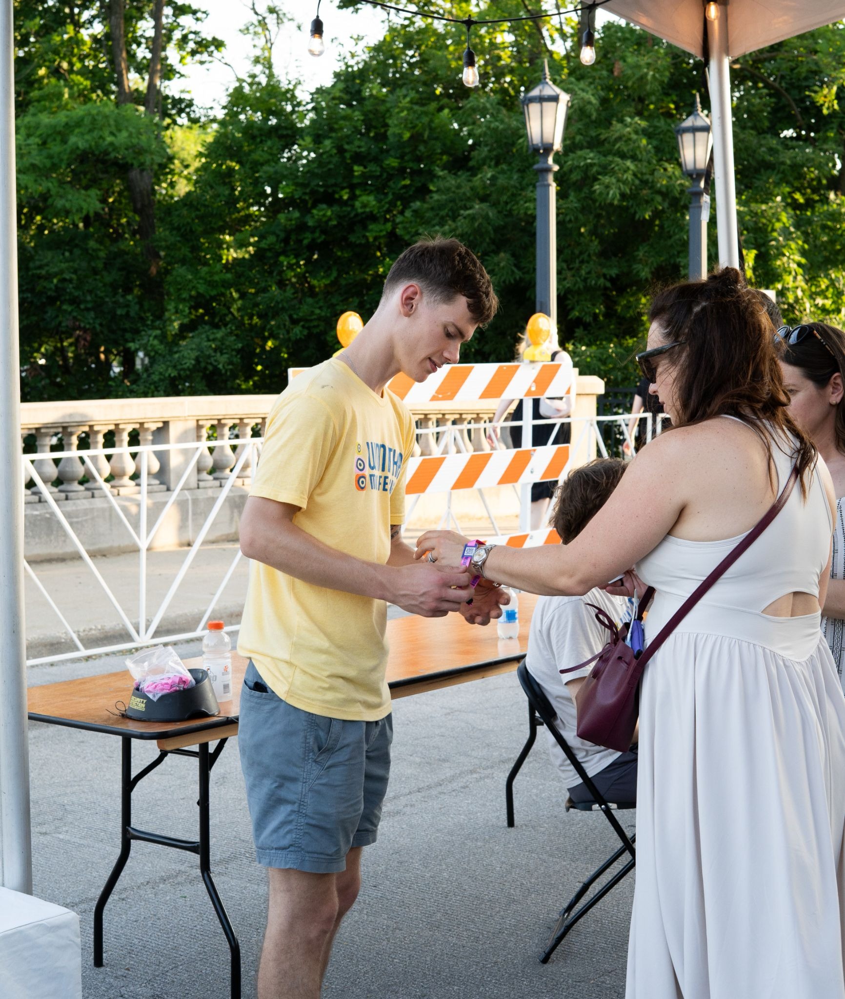 Event staff helping a guest activate an RFID wristband at a tented check-in area