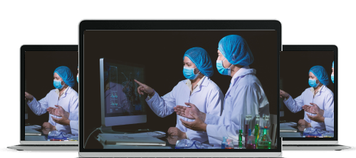 Two scientists wearing lab coats, masks, and blue hair covers analyzing data on a computer screen with laboratory glassware nearby.