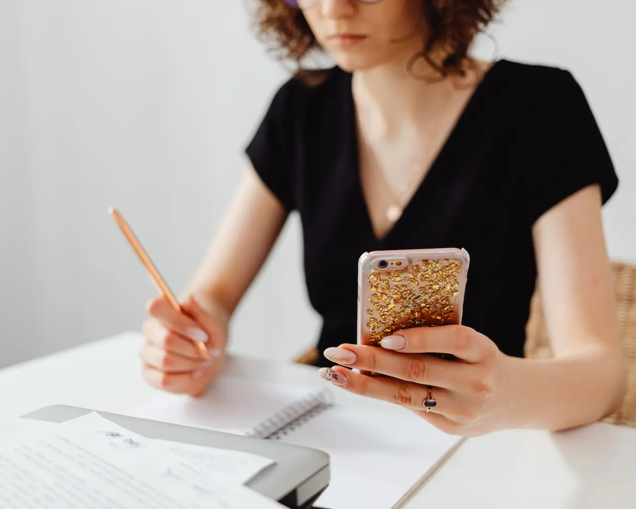 Une femme regardant son téléphone en prenant des notes