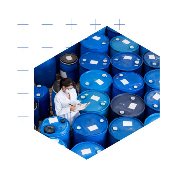 Chemical engineer in lab coat inspecting industrial drums and barrels in hexagonal frame warehouse storage