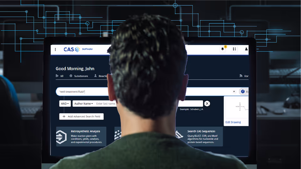 Person viewed from behind looking at a computer screen displaying CAS SciFinder search platform with search query and options.