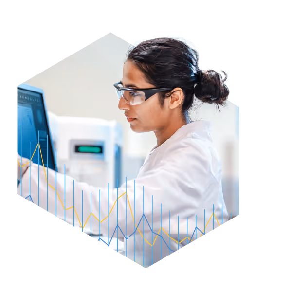 Scientist wearing safety glasses and a lab coat working with a touchscreen monitor in a lab.