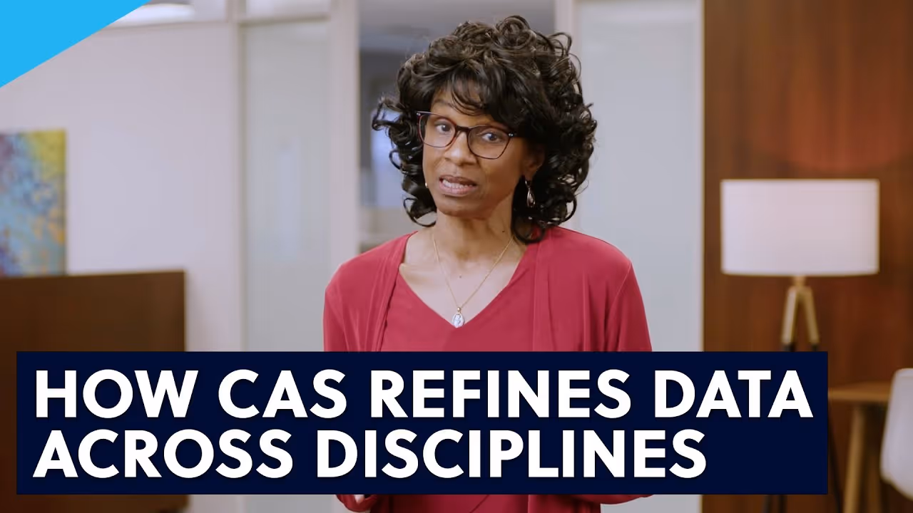 Woman with curly hair and glasses wearing a red top speaking inside an office setting with text overlay about refining data across disciplines.