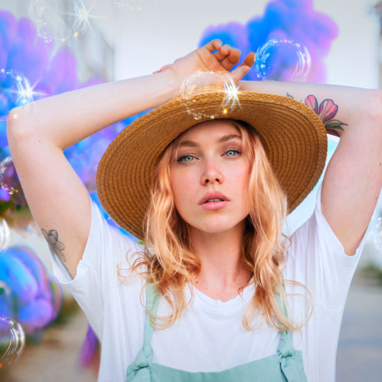 A woman with a white shirt, blond hair and a straw hat with a sparkling filter