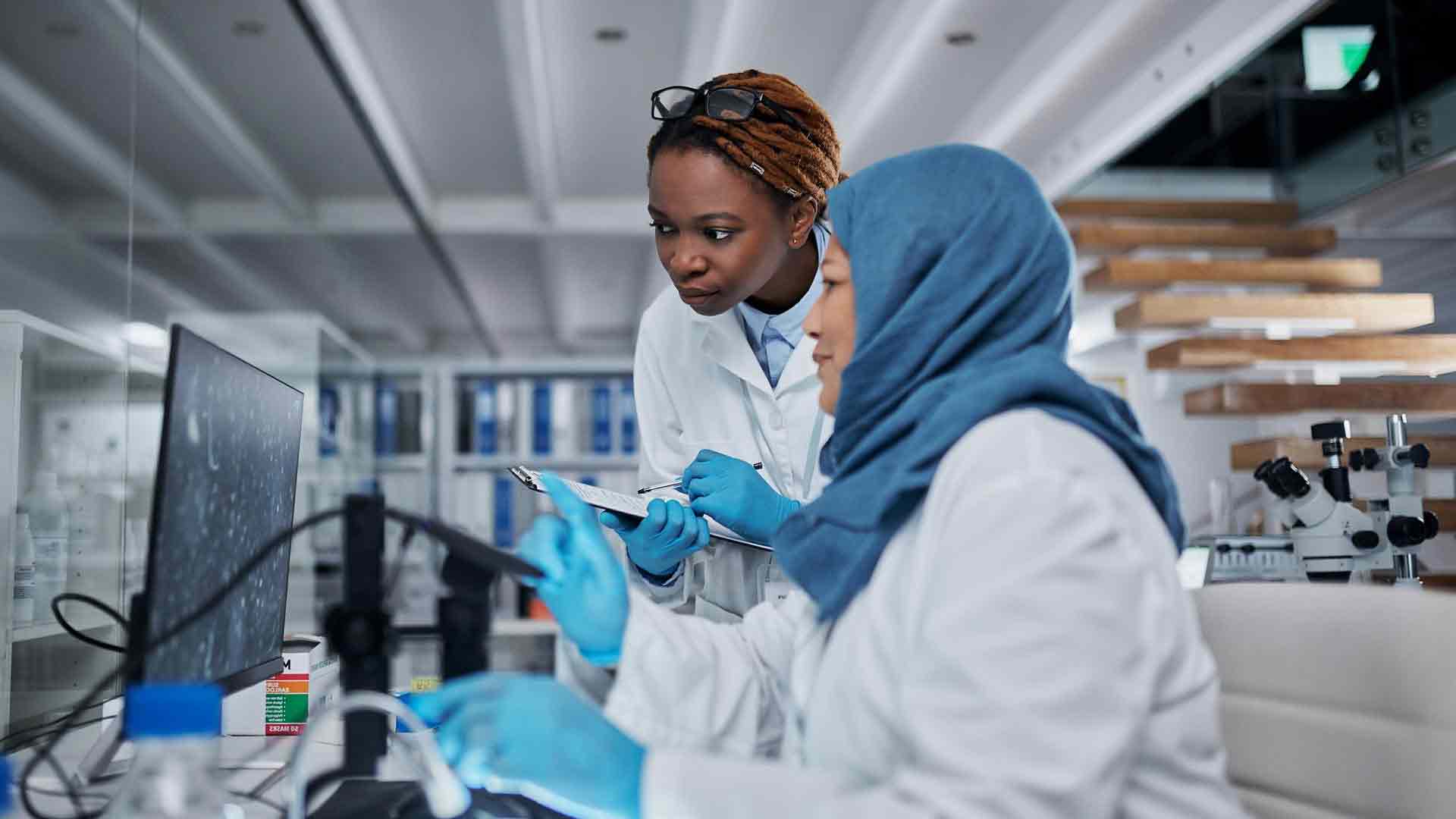 Cropped shot of two female scientists working with a computer and a digital microscope in a laboratory