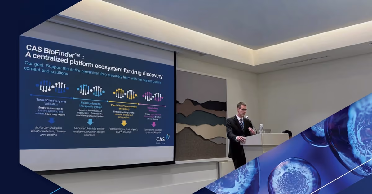 Man in suit gives presentation on CAS BioFinder drug discovery platform in a conference room.