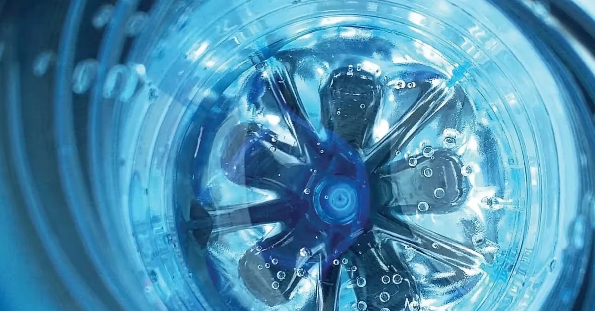 Close-up view inside the bottom of a clear blue plastic bottle with bubbles on its surface.