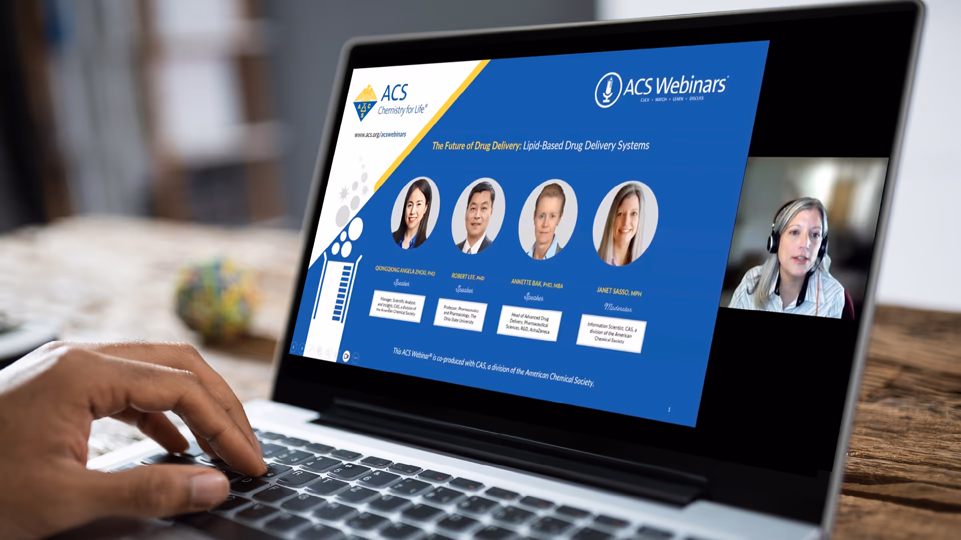 Person watching an ACS webinar with speaker photos on a laptop screen.