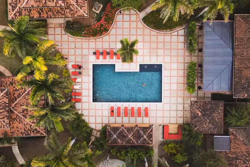 An birds-eye view of Rythmia's saltwater pool and surrounded by lush trees and gardens