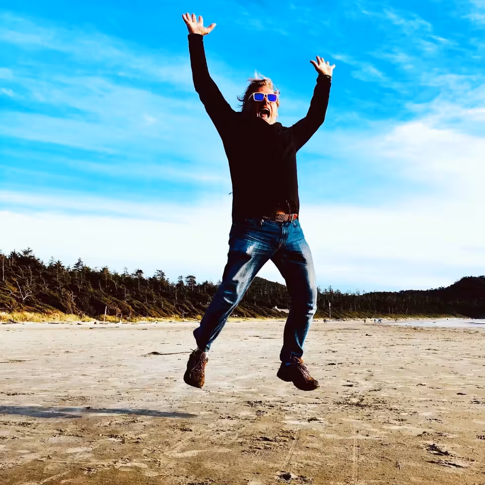 Gerry Powell, Founder and CEO of Rythmia in a field jumping with hands in the air