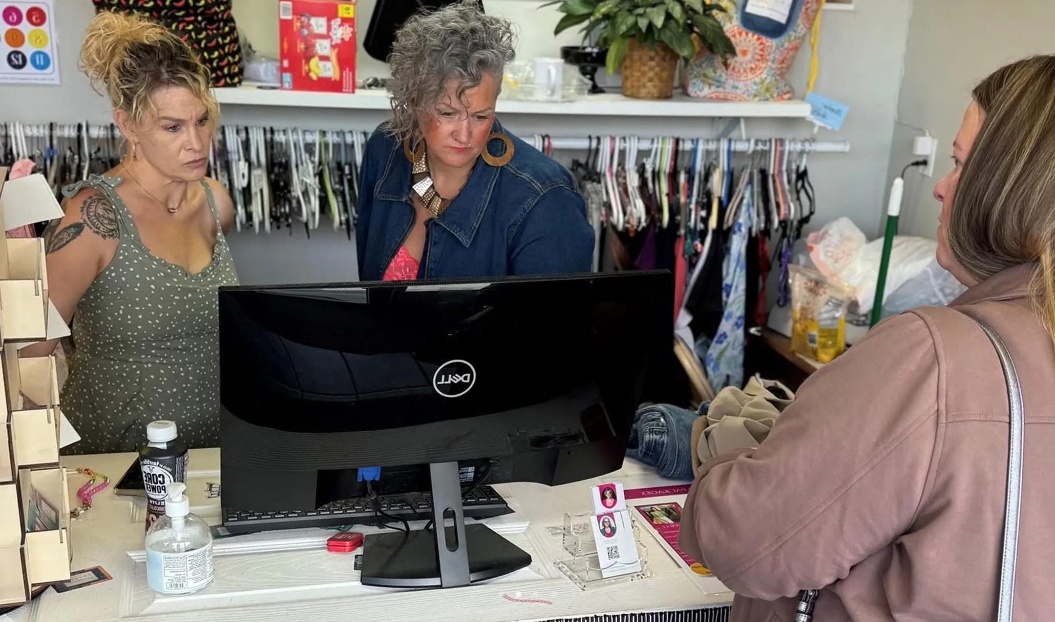 Switch Society staff helping a customer at the checkout counter with thrifted clothes purchase.