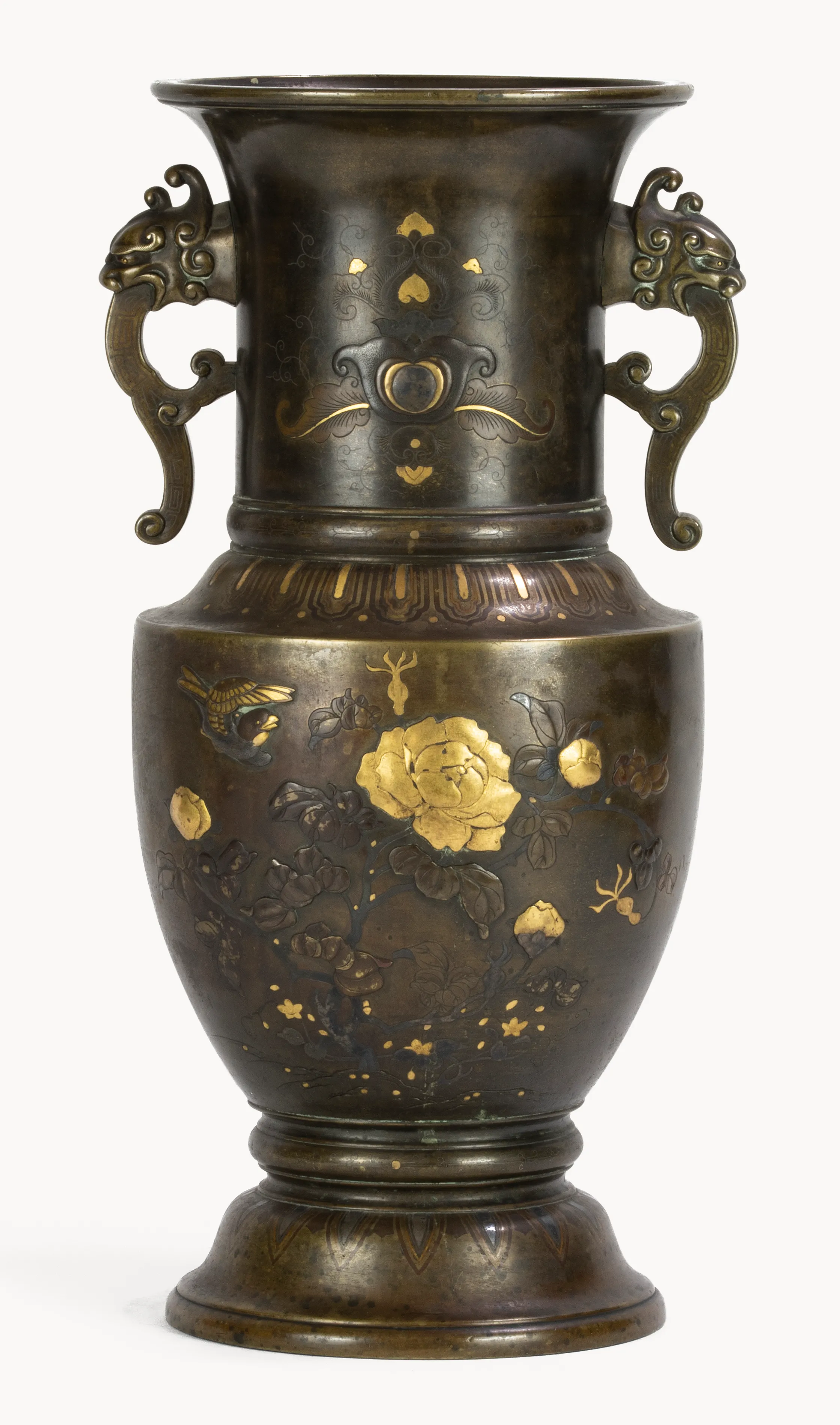 Dunkle Bronzevase mit zwei geschwungenen Henkeln; reich verziert mit eingelegten Goldmotiven wie Blüten, Blättern und einem Vogel, auf gestuftem Fuß