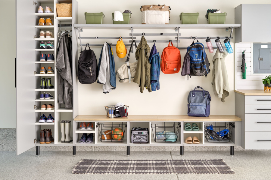 Custom garage organization system with open shelving, shoe storage, wall-mounted racks, backpacks, coats, bins, and sports equipment.