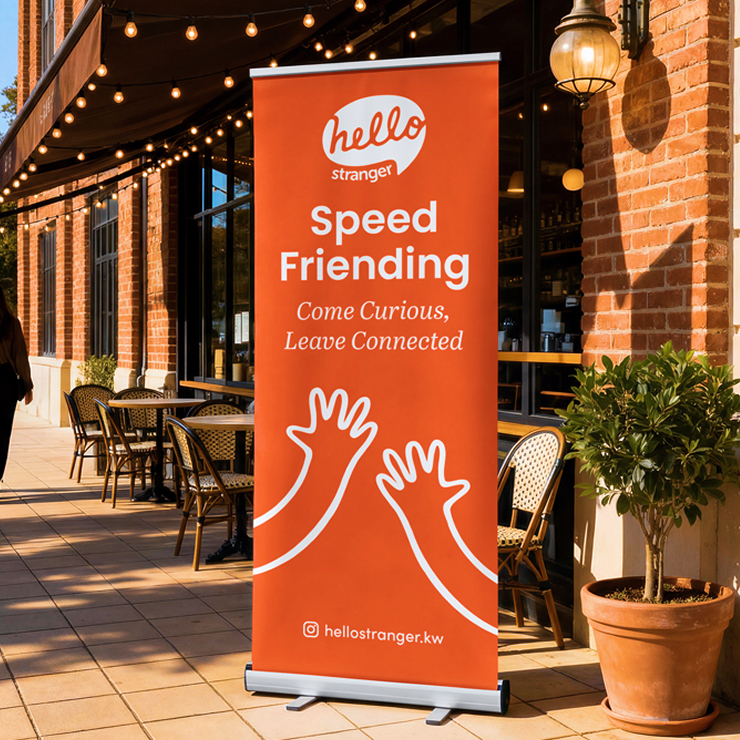 A standing banner with Hello, Stranger branding in a cozy outdoor cafe.