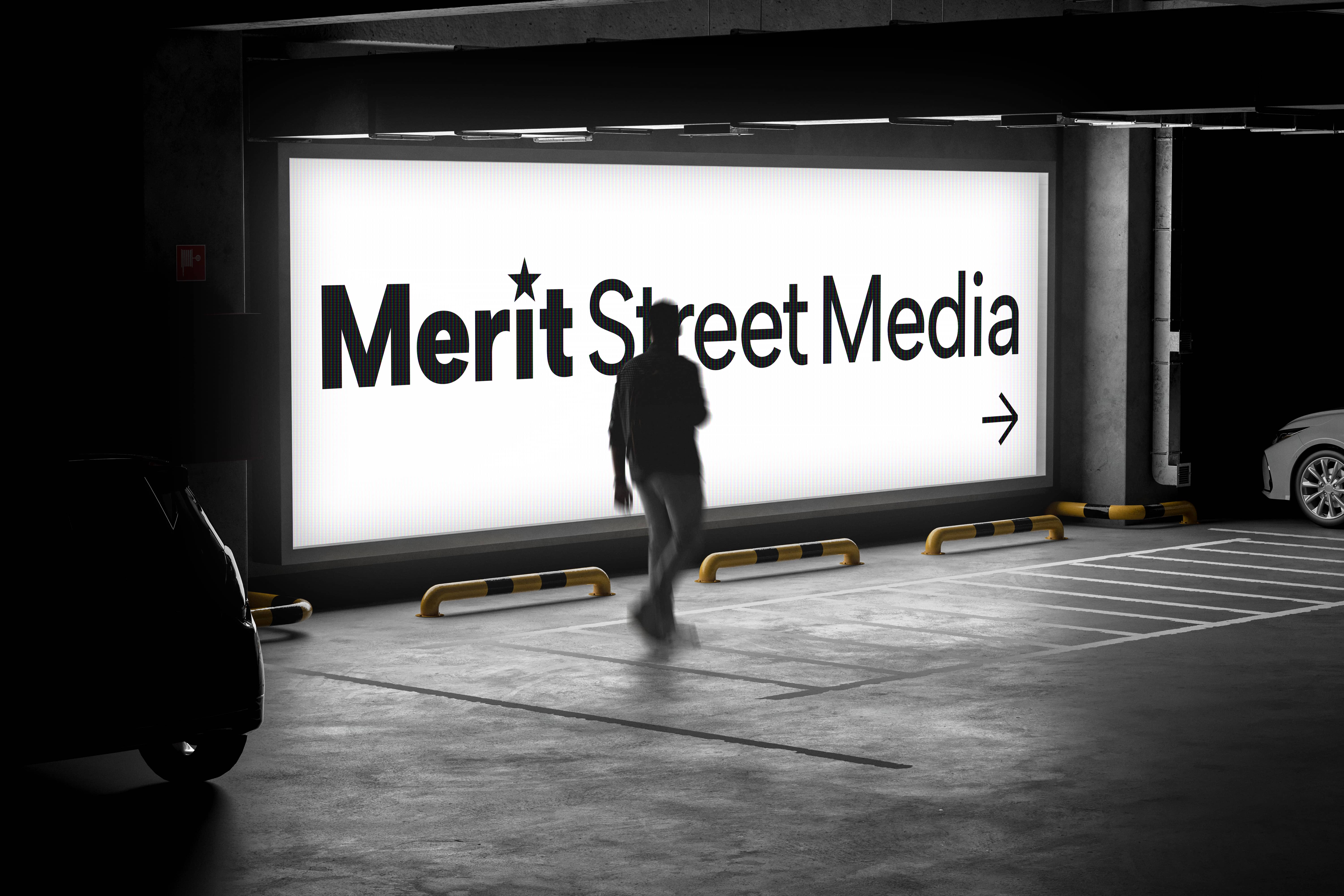 Underground parking lot with signage of Merit Street Media and direction to walk.